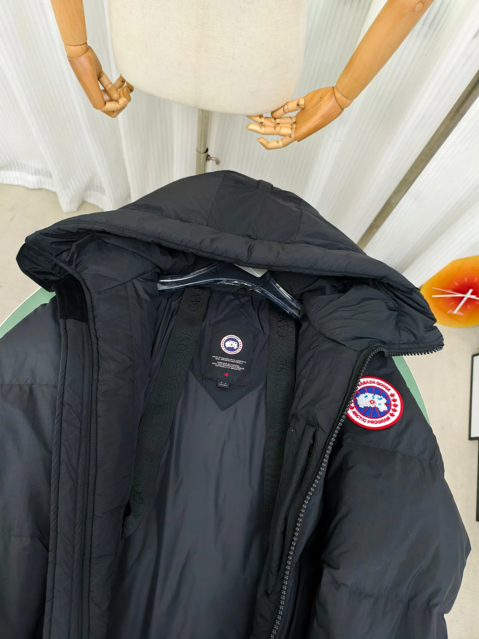 P940 Canada Goose Lawrence Down Jacket The Lawrence Down Jacket provides essential protection for everyday adventures and is made from sustainable Enduraluxe fabric with a durable soft touch. It features a quilted body, an adjustable down hood and a longer hem. Adjustable, down-filled, communicated hood. Two-way center front zipper increases range of motion and ventilation. The chin-protecting suede knit stand-up collar is soft and extra-comfortable. Inset rib-knit cuffs for added comfort and locked in heat. CORDURAD piping at the cuffs hem and reflective double-stripe grip tape at the back. Internal shoulder strap Color: black with red label black with black label azure blue Size: XS-2XL